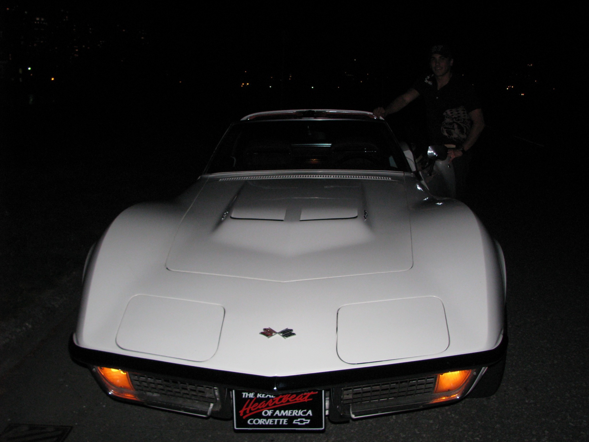 Front view of the Corvette at night with a person beside the car