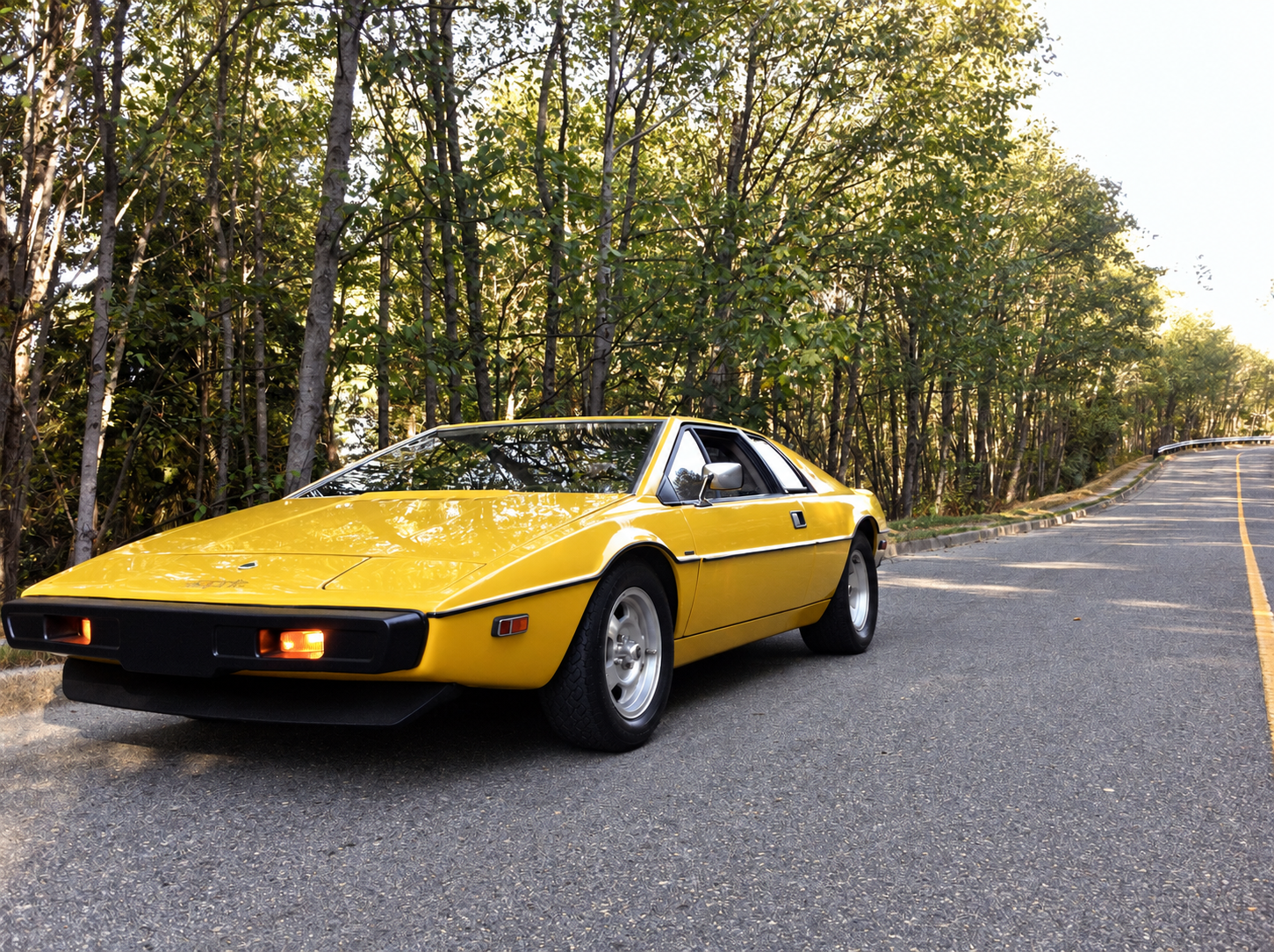 Yellow 1978 Lotus Esprit, front three-quarter view beside a wooded road