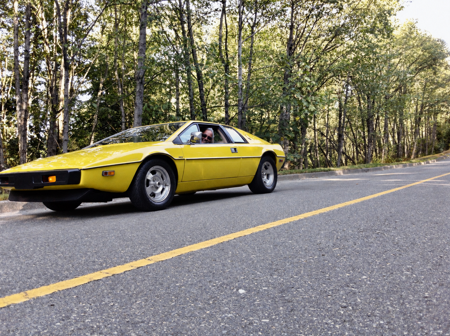 Yellow 1978 Lotus Esprit parked beside a wooded road